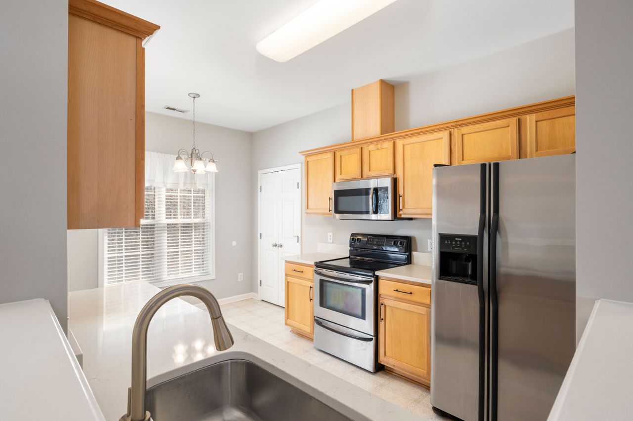 A bright and modern kitchen interior featuring stainless steel appliances and wooden cabinets.